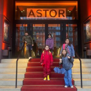 Fünf Kinder stehen vor der Astor Lounge auf einer Treppe.