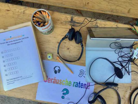 Kopfhörer, Stifte, Ratebögen und ein Schild mit "Geräusche raten!" am Radiofüchse-Medienstand