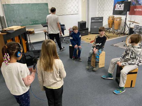 Kinder musizieren mit Percussion Instrumenten. Zwei Mädchen machen Aufnahmen