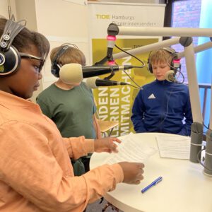 Drei Kinder in einem kleinen Radiostudio am Mikrofon