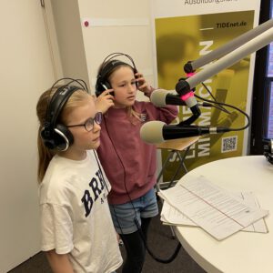 Zwei Kinder in einem Radiostudio am Mikrofon
