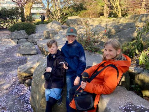 Drei Kinder im Park mit Mikrofon.