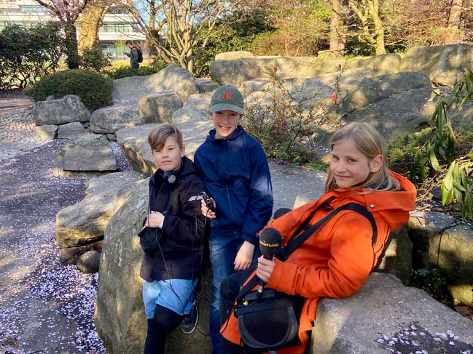 Drei Kinder im Park mit Mikrofon.
