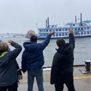 Drei Kinder von hinten, die einem Schiff zuwinken