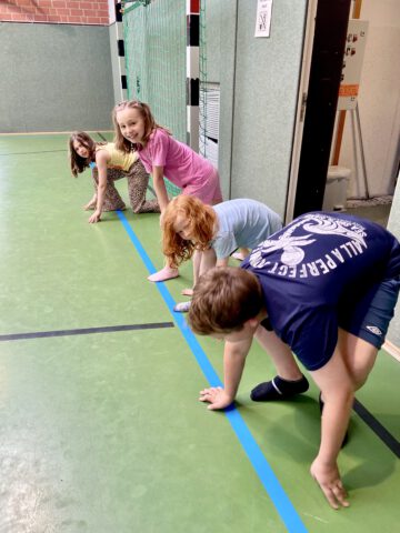 Vier Kinder in Startposition in einer Turnhalle